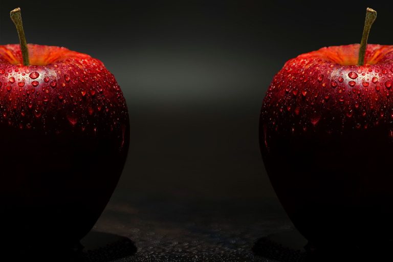 Vibrant red apples with dewdrops against a dark background, showcasing freshness.
