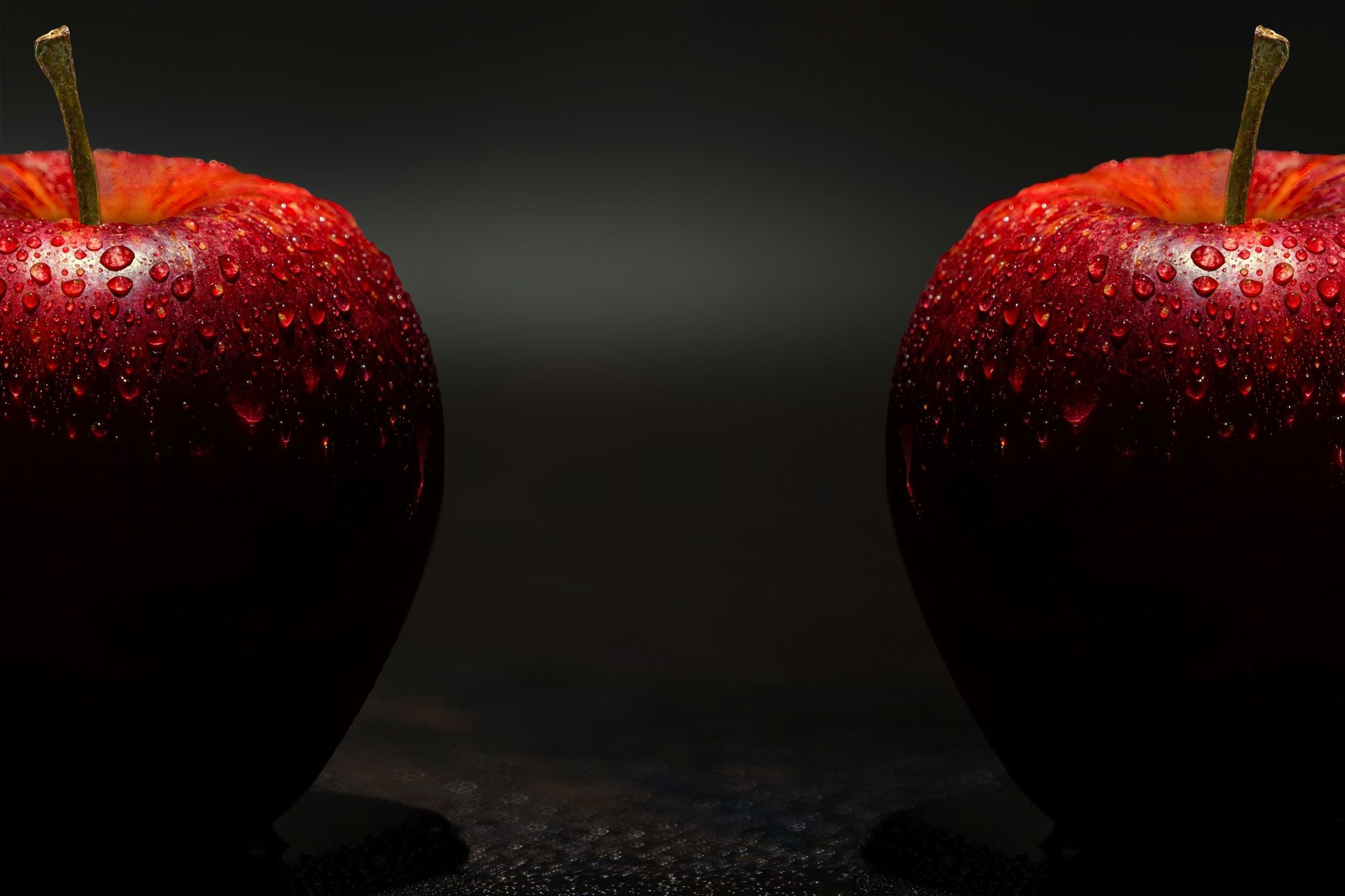Vibrant red apples with dewdrops against a dark background, showcasing freshness.