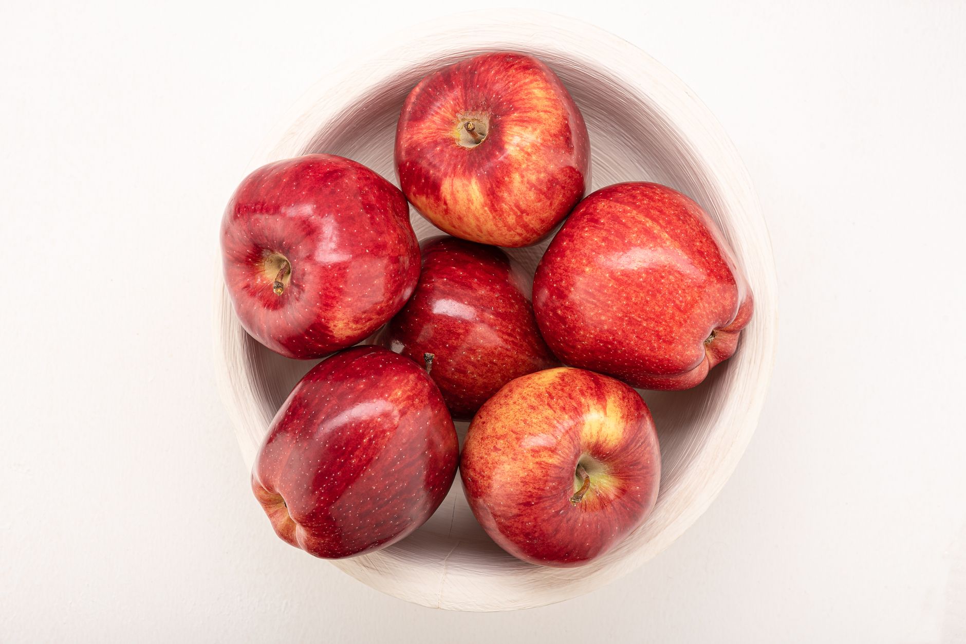 High angle view of fresh red apples in a wooden bowl, highlighting healthy snacking options.